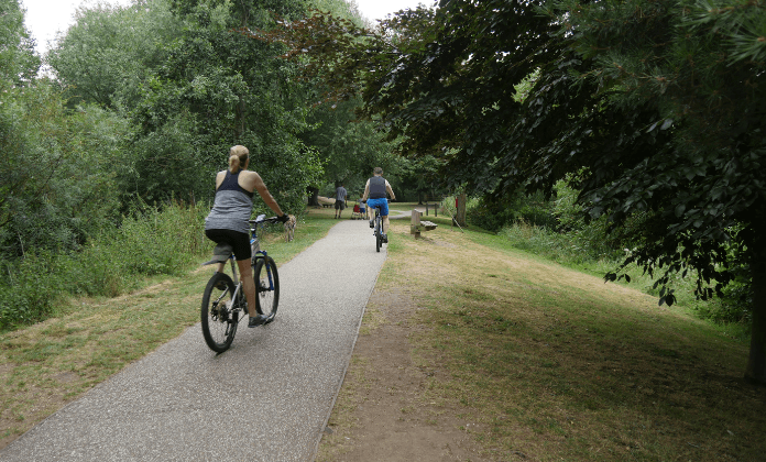 two people cycling at Needham Lakes, seen from behind